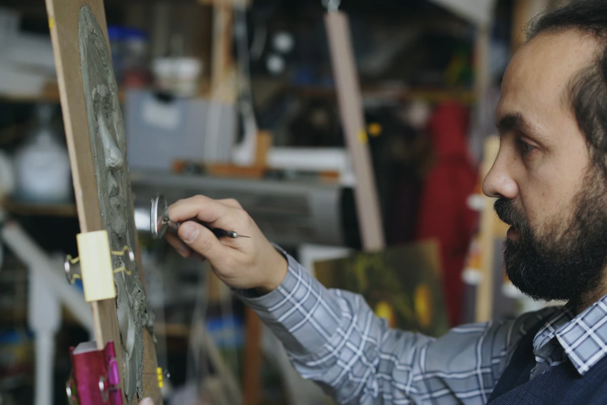 Certamen Alfonso Aramburu 2026: 20.000 € para artistas andaluces 1 Escultor modelando un rostro en su taller – Totenart