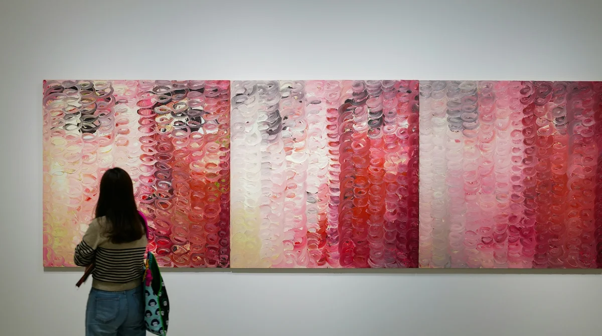 Visitante observando un tríptico de pintura abstracta en una galería – Totenart