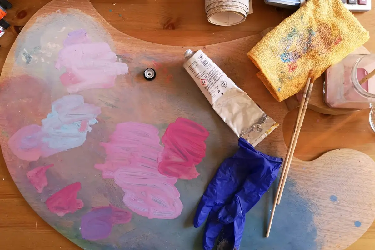 Paleta con mezclas de rosa y lila junto a tubos de pintura y pinceles – Totenart